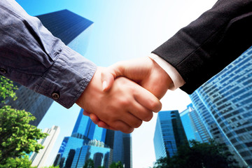 Business handshake, skyscrapers background. Deal, cooperation