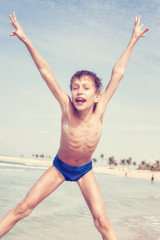 Funny little child jumping on beach and laughing