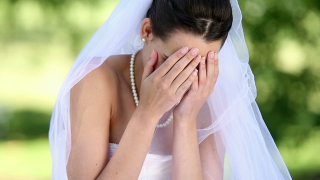 Upset bride sitting on the grass