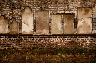 Fototapeta na wymiar Headstones on a brick wall in a cemetary.