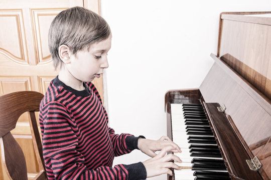 Cute funny little boy playing piano