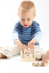 Little cute boy playing with building blocks. Isolated on white.