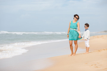 Mother and son walking along a tropical beach