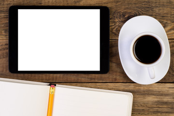 Tablet, cup of coffee and notebook on wooden desk