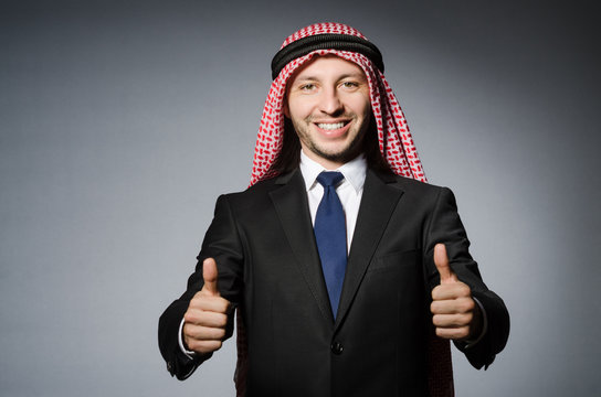 Arab businessman with thumbs up againt grey background