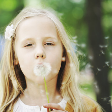 Cute child and dandelion on greenery background
