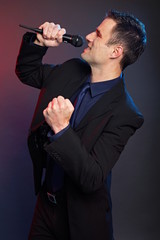 Karaoke with handsome man in suit on dark background