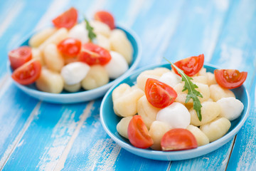 Boiled gnocchi served with mozzarella, red tomatoes and arugula