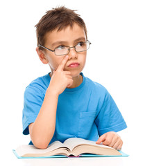 Young boy is daydreaming while reading book