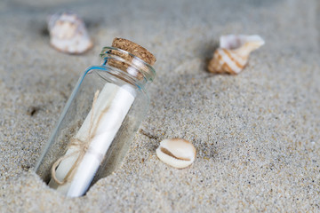 Mensaje en una botella de cristal en la arena de la playa