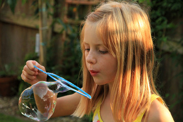 A young girl, blowing a big bubble on a summers day