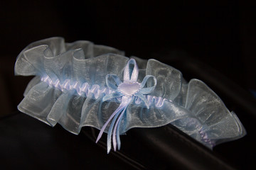 Light blue lace garter arranged on dark leather