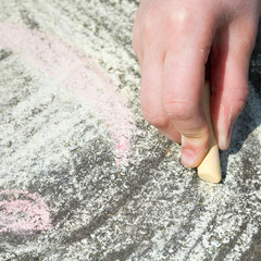 girl drawing with colored chalk on pavement