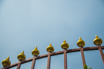 Golden decoration of steel fence with blue sky