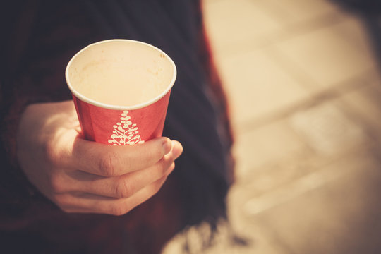 Closeup on a young woman holding a paper cup