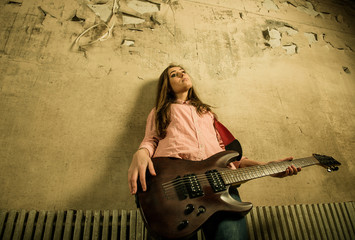 woman with guitar at old wall