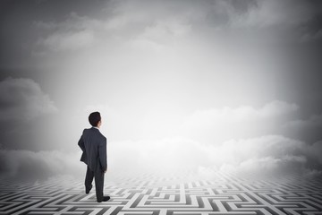 Composite image of businessman standing with hand on hip