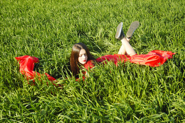 young lady in red dress lie on field