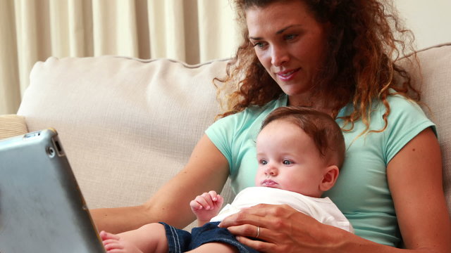 Mother using tablet pc with baby son on her lap