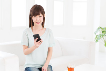 部屋でスマートフォンを見る女性