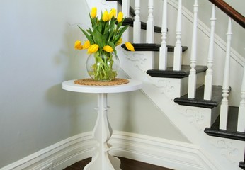 Yellow tulips on a round table beside heritage staircase