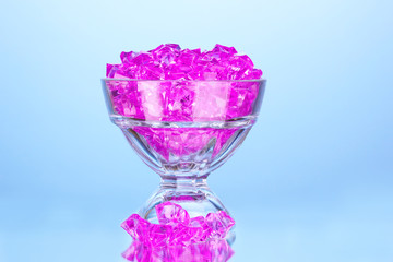 A glass with pink decorative stones on blue background close-up