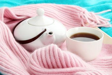 Cup and teapot on tray with scarf on fabric background