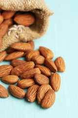 Almonds in sack on  color wooden background
