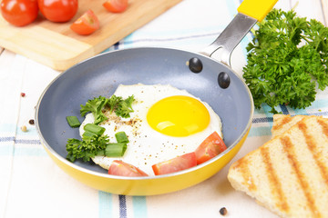 Scrambled eggs and bacon on frying pan on table close-up