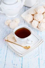 Cup of tea with meringues on table close-up