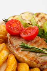 Grilled steak with fried potato pieces and grilled vegetables