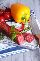 Tasty salami sausage, vegetables, knife and spices