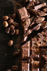 Chopped bar of chocolate on wooden background