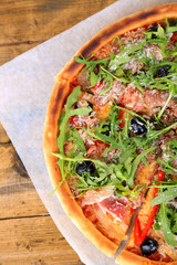 Pizza with arugula on color wooden background