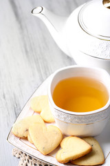 Lavender cookies and cup of tasty tea on color wooden