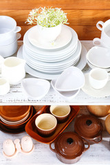 Different tableware on shelf, on wooden background