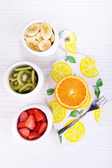 Various sliced fruits in bowls on table close-up