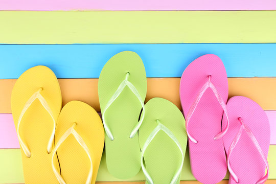 Bright flip-flops on color wooden background