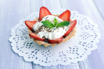 Tasty tartlet with strawberries on table close-up