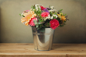 Flower bouquet in bucket on wooden table