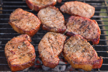 Thick seasoned pork chops cooking on the grill