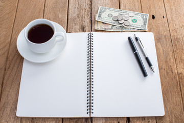 Blank notebook with pen and coffee cup on old wooden background