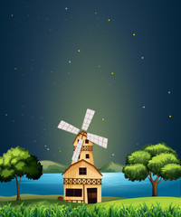 A wooden barnhouse at the river with a windmill