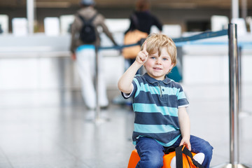 Little boy going on vacations trip with suitcase at airport