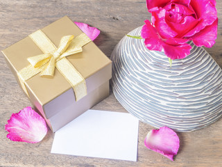 Gold gift box with card and rose in vase