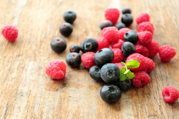 Fresh blueberries and raspberries with green mint leafs