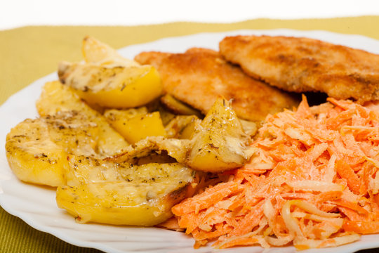 Dinner meal. Fried chicken roasted potatos and carrot salad.