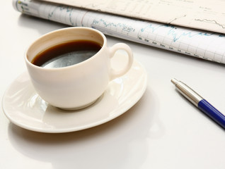 cup of coffee near the laptop and newspapers
