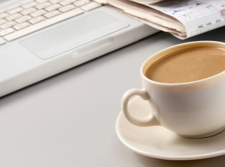 cup of coffee near the laptop and newspapers