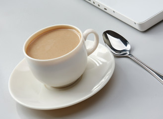cup of coffee near the laptop and newspapers